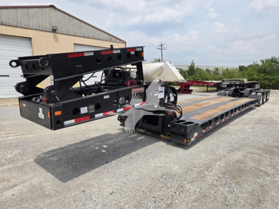 Fontaine 60Hd MX lowboy trailer in transport position showing gooseneck and deck with black frame, white hydraulic components, and wood deck sections.