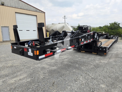 New Fontaine 60HD MX lowboy trailer shown from rear-left side with gooseneck and multiple axles, side ramps, and storage boxes.