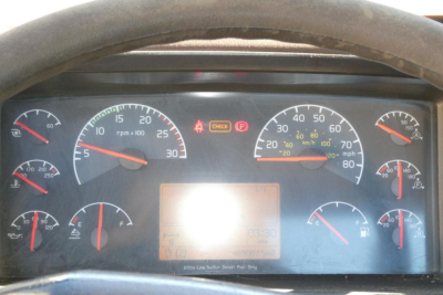 Volvo VNM cab interior dashboard showing gauges; central display; warning lights. Dials include rpm x100, mph, fuel, temp, oil pressure indicators.