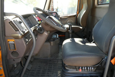 Volvo VNM cab interior with steering wheel, dash display, and driver seat visible in daytime. Text on controls and dashboard present.