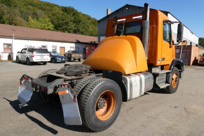 Volvo VNM42T truck in orange color viewed from rear-left side showing chassis and cab.