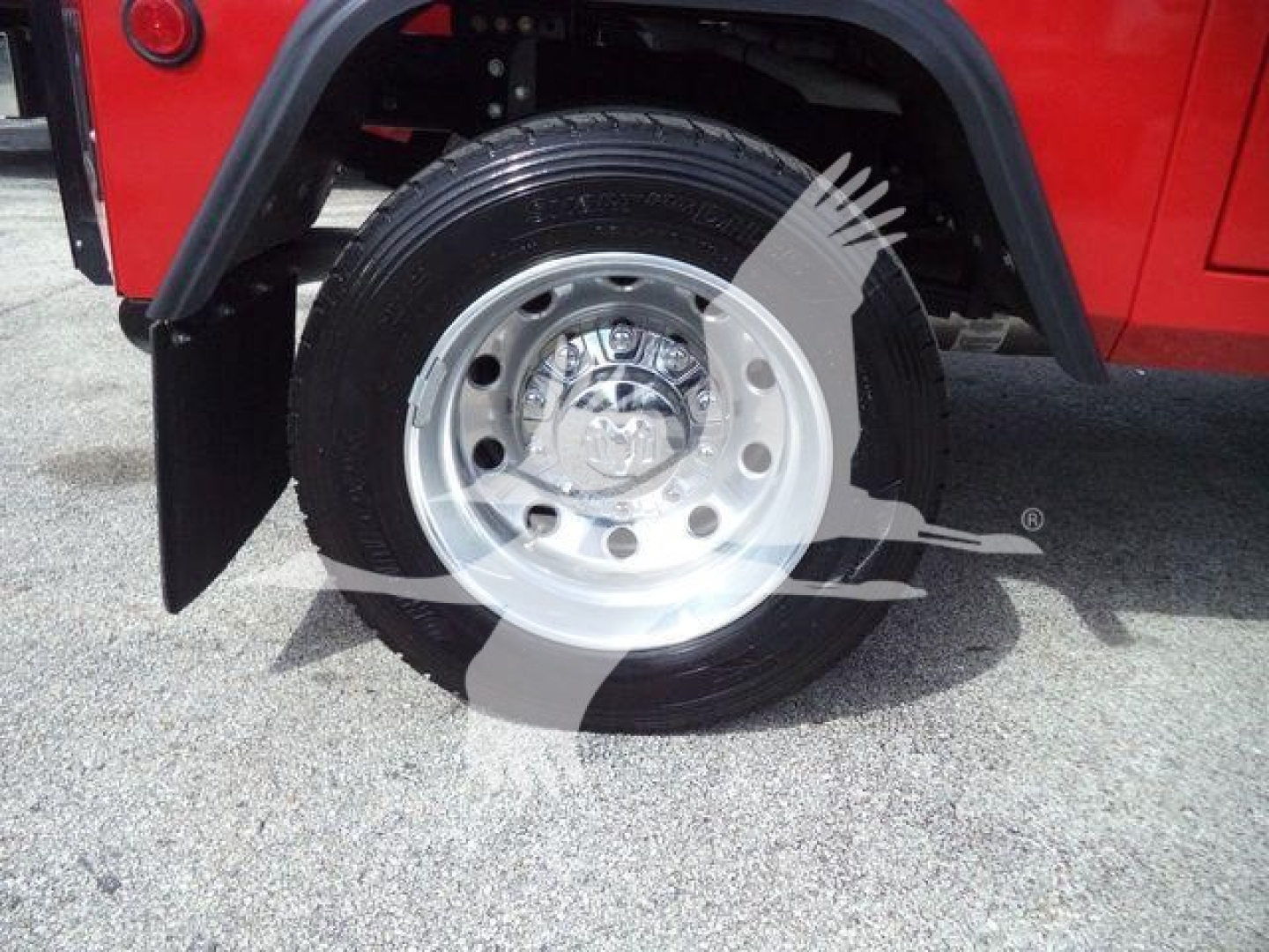 Wheel and tire on a red Ram 5500 SLT truck, front wheel with silver hub, black tire, fender and mud flap visible.