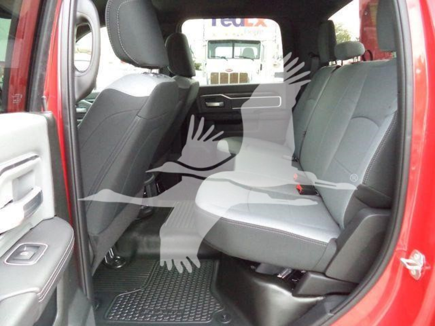 Ram 5500 interior view showing rear bench seats and front seats, red exterior, black floor mats, gray upholstery, partial back door open.
