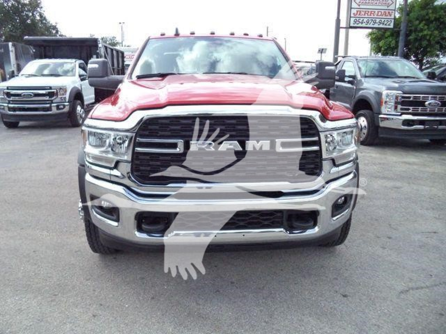Front view of a red 2024 Ram 5500 SLT pickup truck with chrome grille and bumper, parked in a dealership lot.