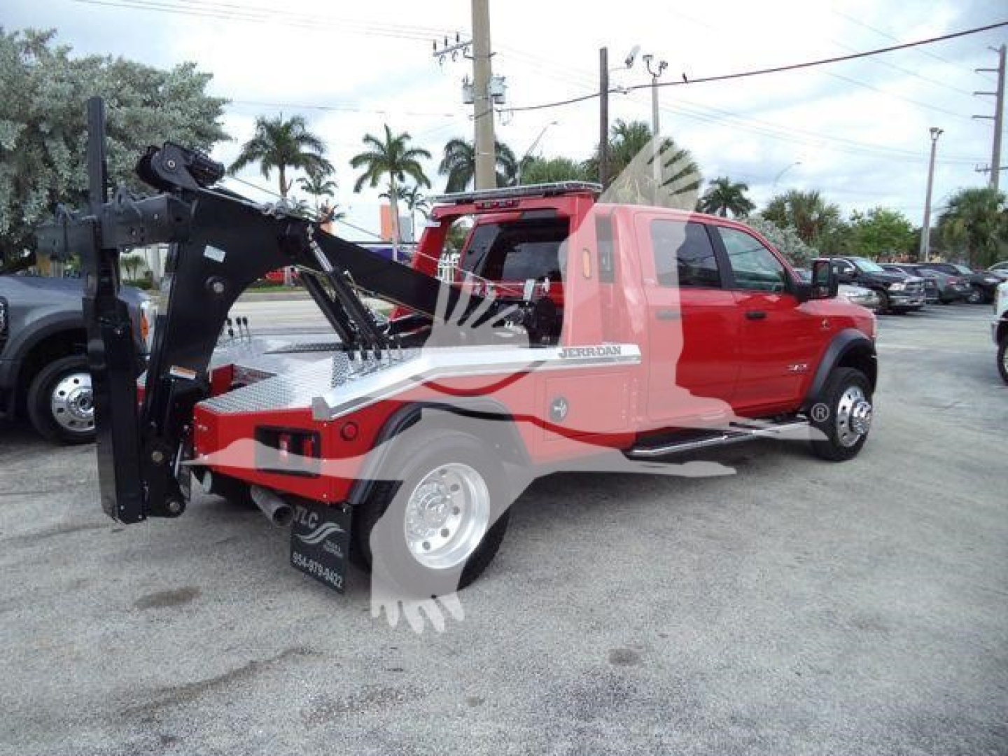 Ram 5500 tow truck with front-mounted hydraulic winch system and red cab, side view showing winch apparatus and industrial equipment on flatbed.