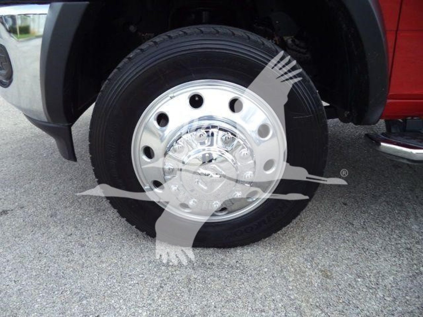 Wheel and tire of a Ram 5500 truck showing chrome hubcap and steel rim with vehicle body in red