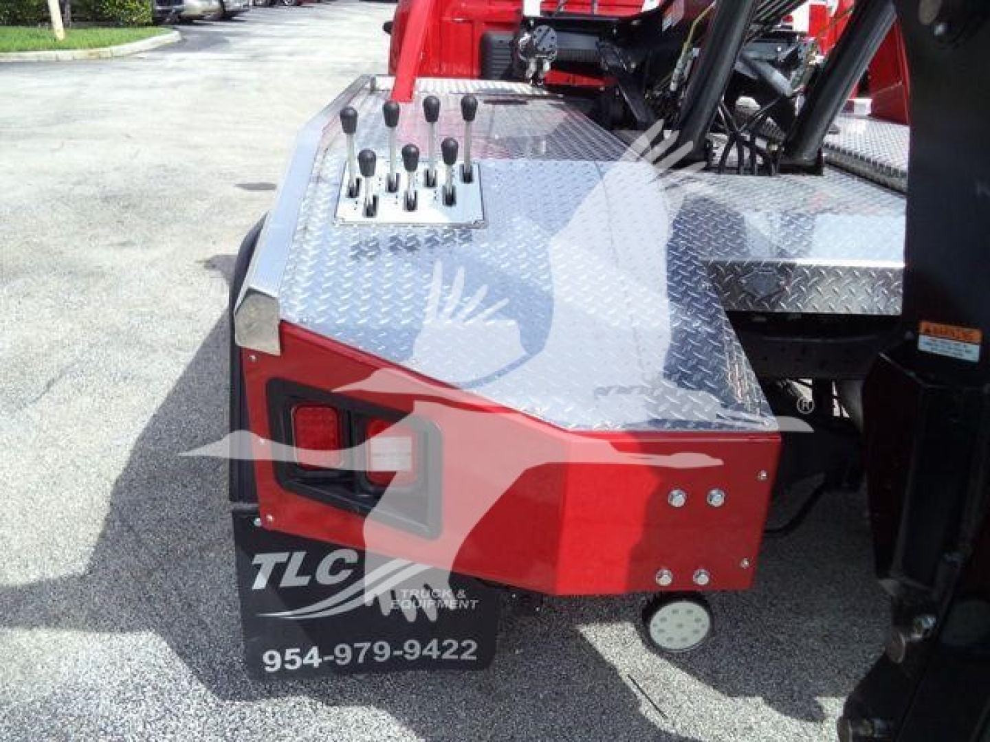 Truck bed side showing control levers and diamond plate toolbox on a Ram 5500 winch conversion with TLC logo and phone number.