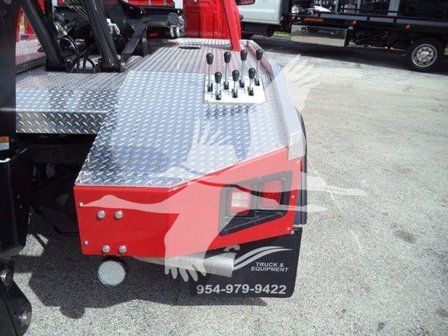 Ram 5500 winch truck front fender area showing diamond plate tool platform and control levers with stock tag and phone number.