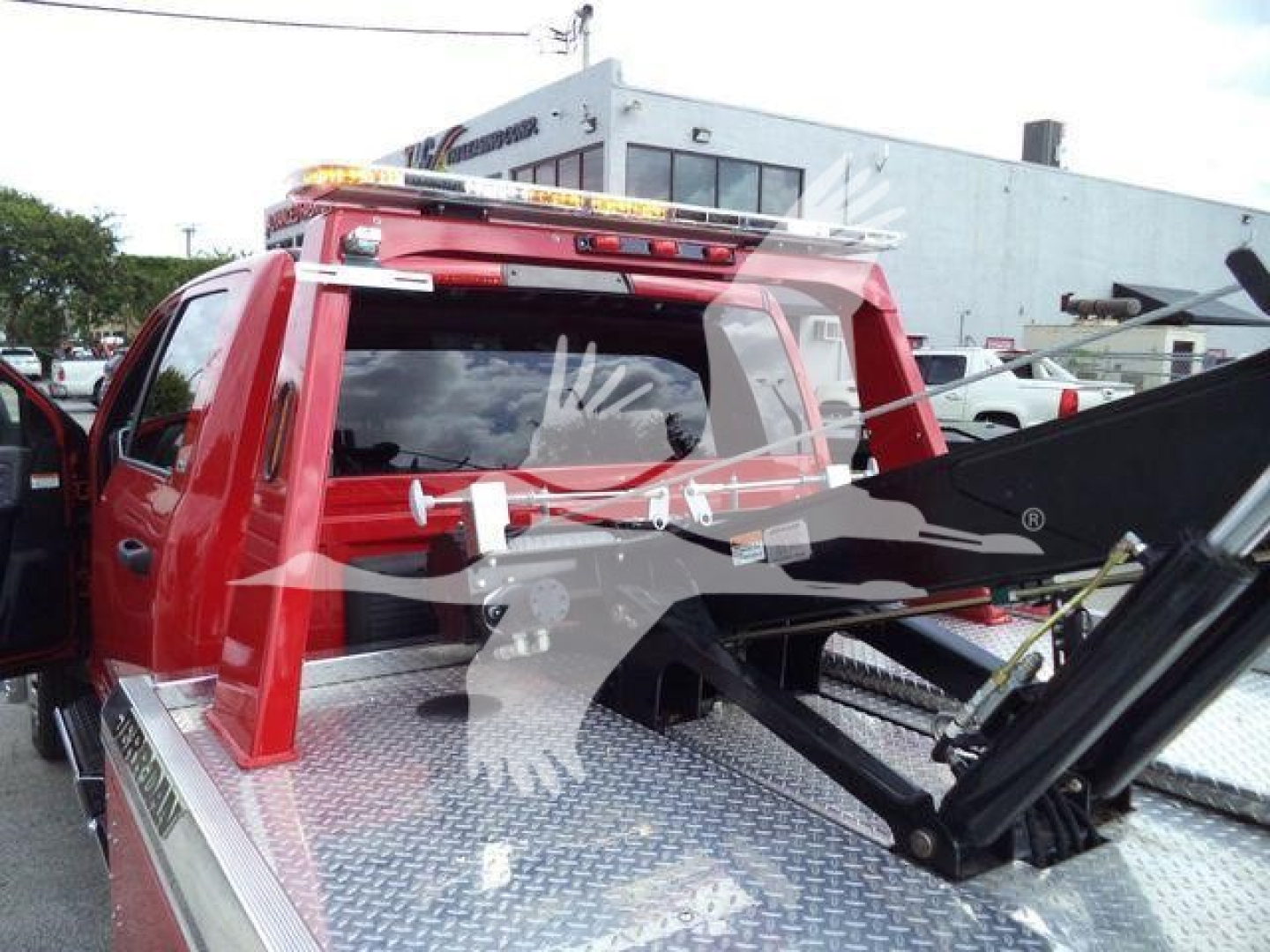 Ram 5500 pickup truck with a winch and metal bed platform, red cab, tow apparatus, and warning lights on top of cab. Stock info not visible.
