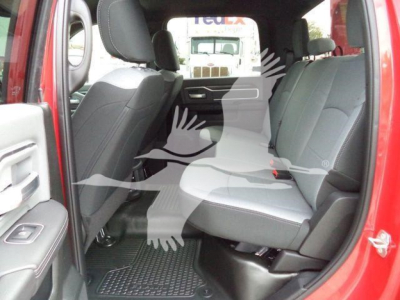 Ram 5500 interior view showing rear bench seats and front seats, red exterior, black floor mats, gray upholstery, partial back door open.