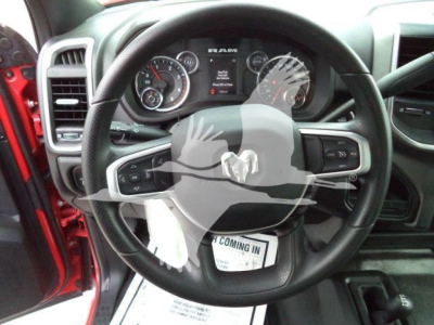 Dashboard and steering wheel view of a 2024 Ram 5500 SLT; visible instrument cluster, Ram emblem on steering wheel, floor mat shows ‘COMING IN’ text.