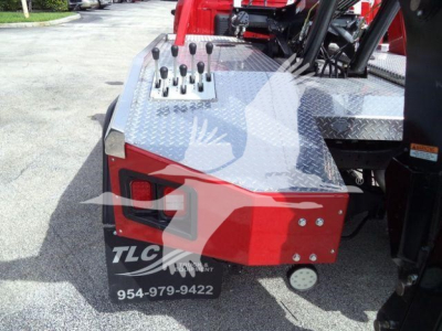 Truck bed side showing control levers and diamond plate toolbox on a Ram 5500 winch conversion with TLC logo and phone number.