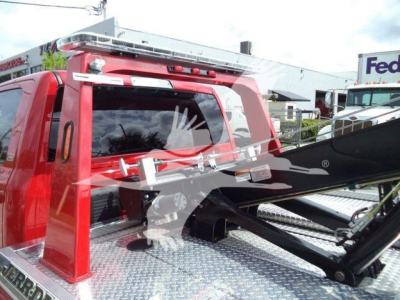 Ram 5500 winch truck rear cab view with tire rack and hydraulic winch arm in red vehicle.