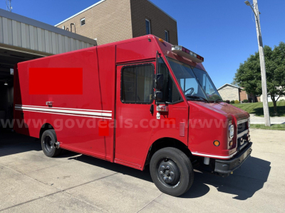 Red Freightliner MT45 cab and chassis truck with white stripe, side service door, and black wheels; visible front grille and cab windows.