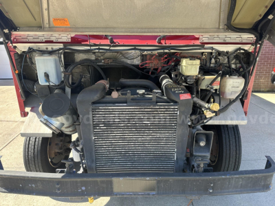 Front engine bay of a Freightliner MT45 chassis showing radiator, coolant reservoir, power steering components, and belts.