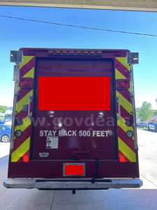 Rear view of a red Freightliner MT45 cab and chassis with high-visibility chevrons, doors closed, text 'STAY BACK 500 FEET' visible on the rear hatch, license area obscured.
