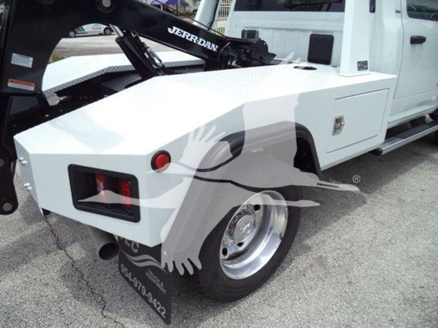 Truck rear side showing white Ram Slt with Jerr-Dan tow hoist and wheel, side toolbox, and chrome wheel.