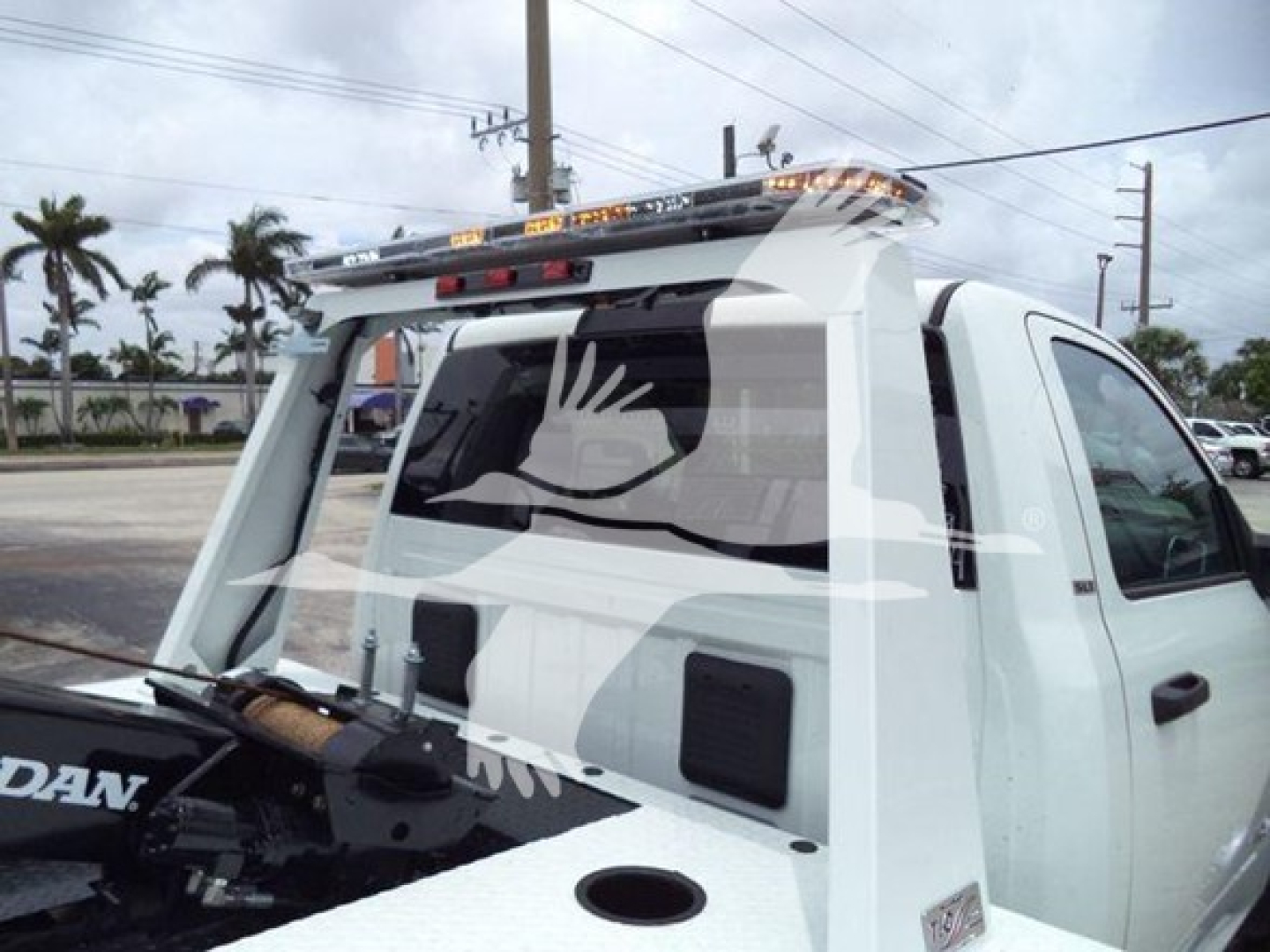 Truck rear window with vinyl decal, Ram truck with winch setup and roof rack mounted on white cab; visible equipment includes winch and tools in bed area.