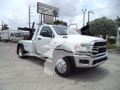 Ram pickup tow truck configuration showing front grille and wheel, with white paint and equipment mounts.