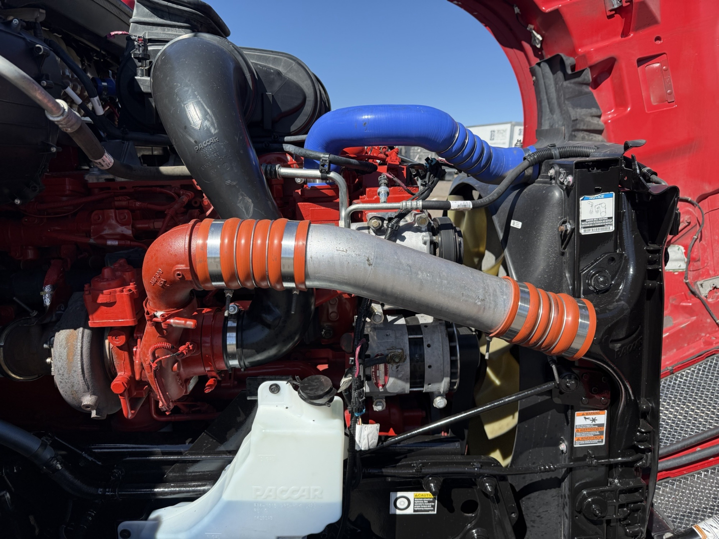 Kenworth T680 engine bay showing turbocharger and intercooler pipes and blue radiator hose