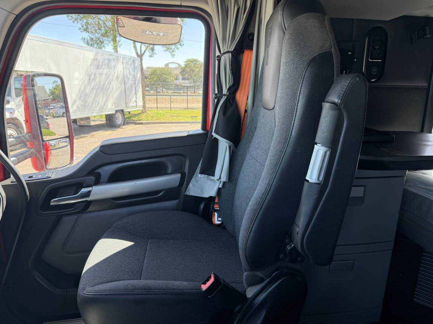 Kenworth T680 truck interior seat view from driver door with seat belts and cabin cabinets.