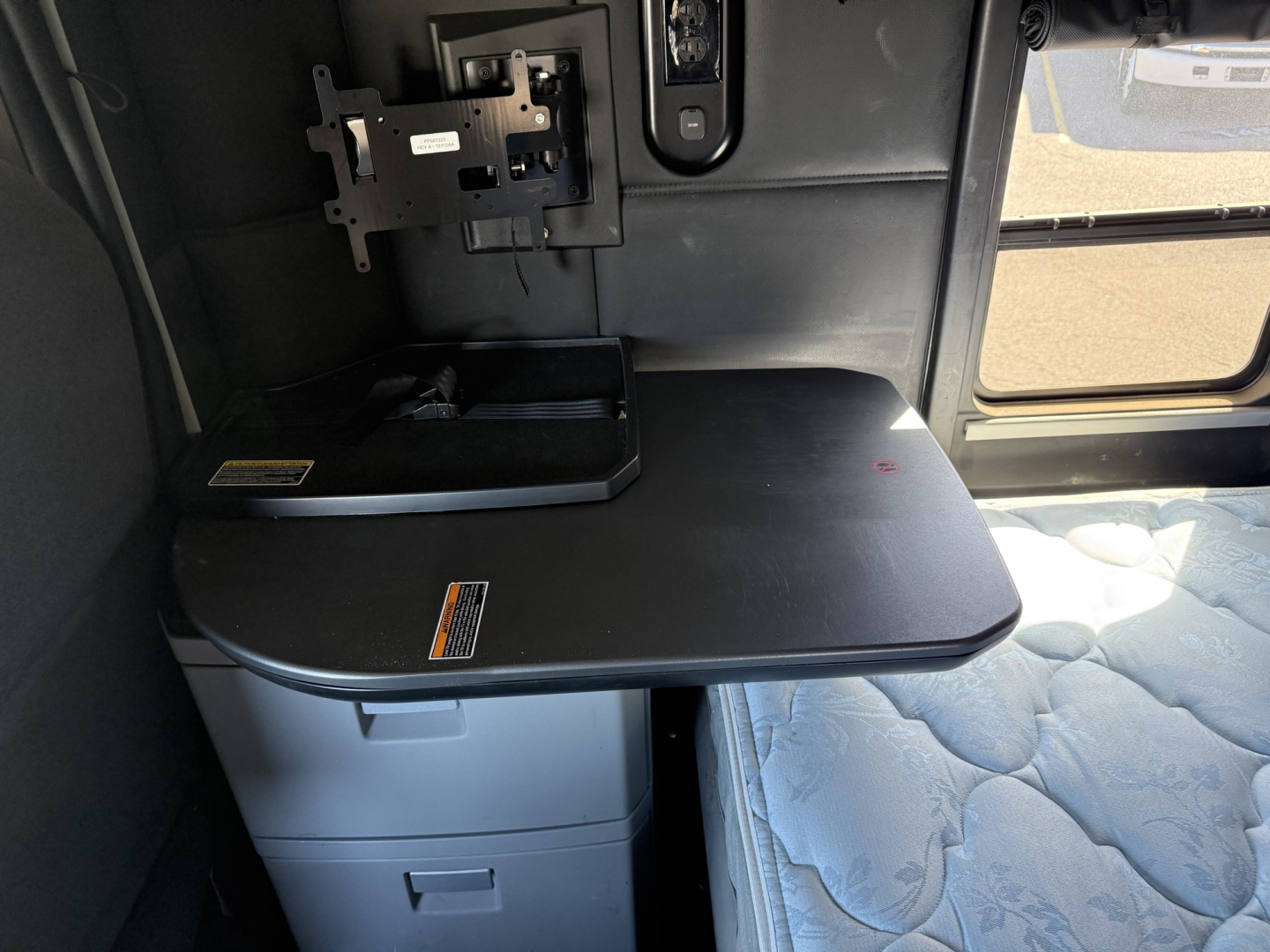 Kenworth T680 sleeper cab interior showing a foldable desk/table with storage drawers and a mounted monitor bracket.