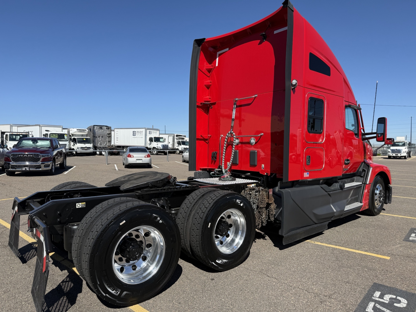 Kenworth T680 tractor rear view showing red sleeper cab and dual rear axles with chrome wheels, trailer hitch, and exhaust pipes visible.