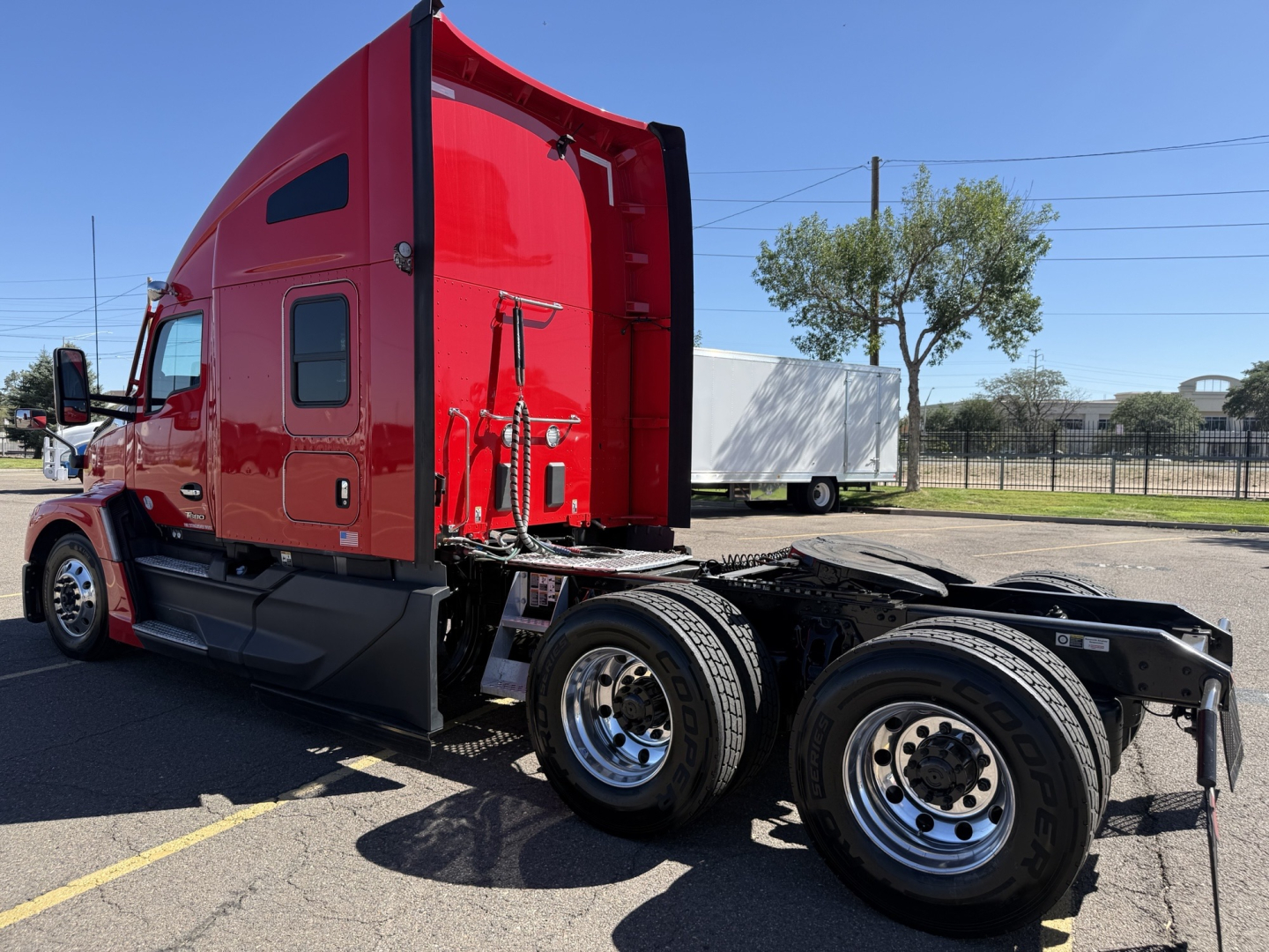 Kenworth T680 tractor cab side view showing rear wheels and chassis with red paint and sleeper cab profile.