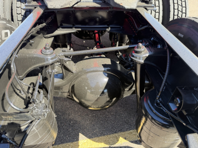 Kenworth T680 chassis view showing rear differential and suspension components under the cab; visible air springs and driveline behind the cab.