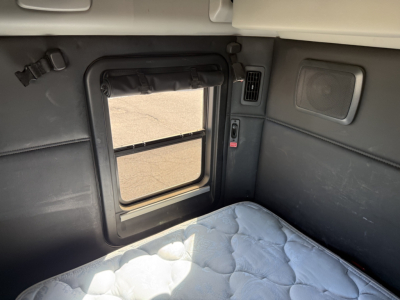 Kenworth T680 sleeper cab interior window area with window shade and sleeper bed visible.