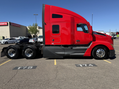 Kenworth T680 sleeper cab in red side view showing tractor with dual rear axles, chrome fuel tanks, and black chassis in a parking lot.
