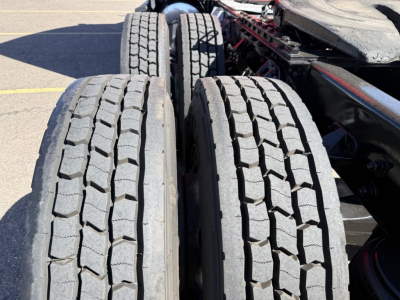 Two rear dual tires on Kenworth truck chassis with visible tread pattern and part of frame.