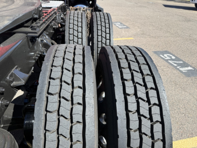 Kenworth T680 truck chassis rear showing dual rear axles and heavy-duty tires, with tread pattern visible on two left tires in focus.