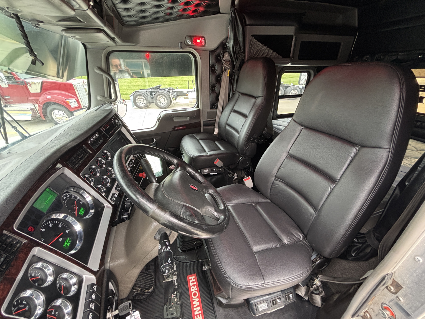 Kenworth W900L truck interior showing driver seat, steering wheel, and dashboard with gauges