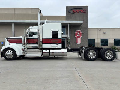 Kenworth W900L conventional sleeper truck side view showing white and burgundy cab with chrome exhaust stacks and dual rear axles.