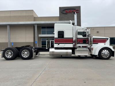 Kenworth W900L semi truck cab and chassis side view with white and maroon stripe showing 3-axle configuration and fuel tanks.