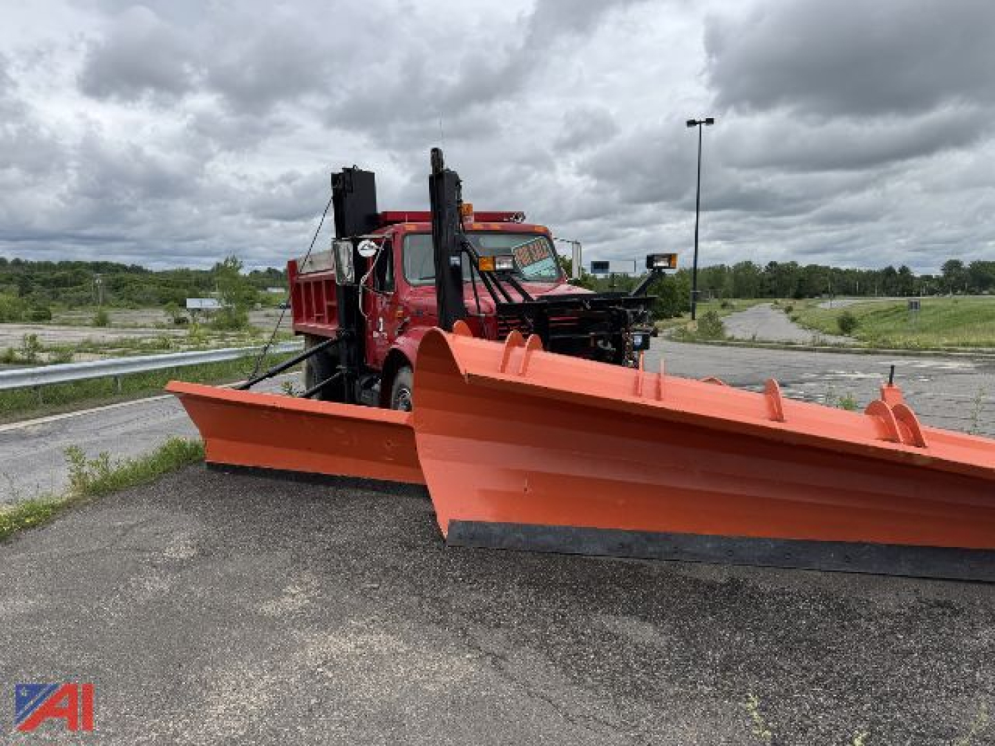 International dump truck with a large orange snow plow and wing attachment front view showing plow blades and mounting frame.
