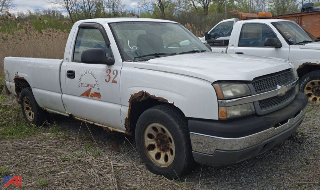 White 2005 Chevrolet Silverado 1500 pickup with rust on rear fenders, number 32 on door, text 'HIGHWAY 4' near front fender, black grille, two-tone bumper, other older trucks in background.