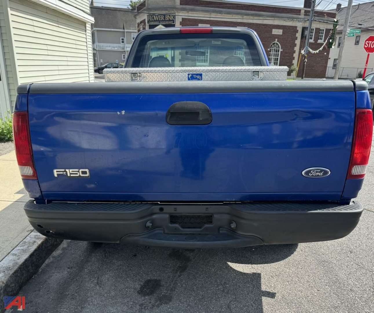 Ford F-150 tailgate showing F-150 badge and Ford oval logo on blue pickup truck bed with black bumper.