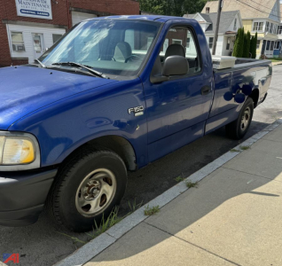 Ford F-150 pickup truck 1998 model in blue, extended cab with long bed, side view showing F-150 badge on front fender and wheel, 2WD