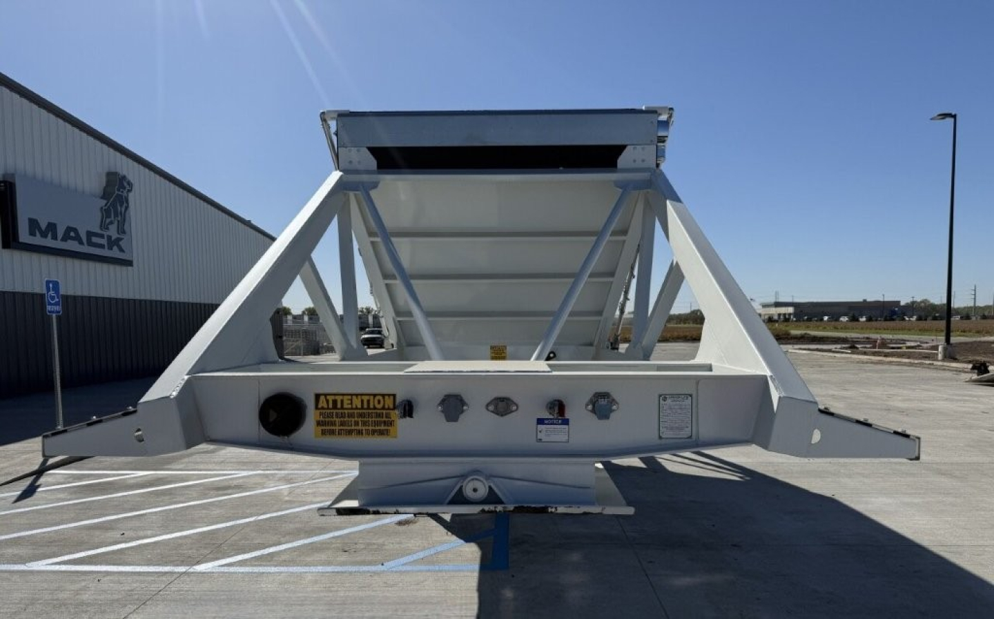 Dump trailer frame showing skeletal Armor Lite SBD40 spring with triangular rails, warning label, and mounting hitch.