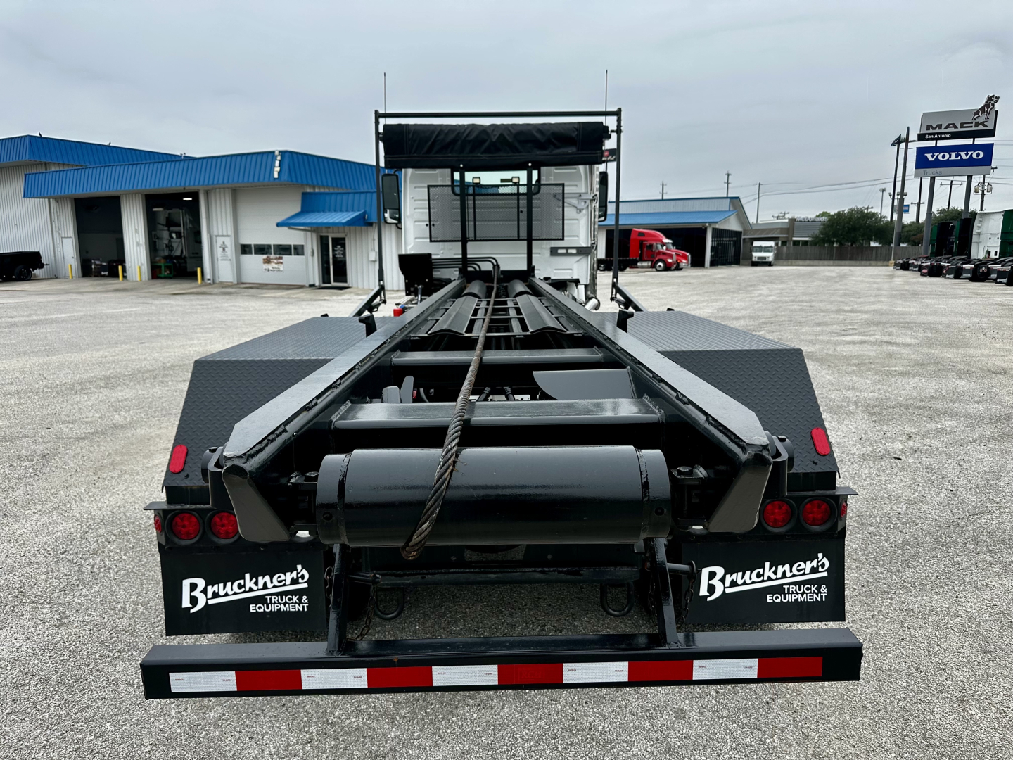 Rolloff truck chassis from rear view with heavy-duty frame, hydraulic winch, and bunks; Buckner Trucks & Equipment branding on rear fenders.