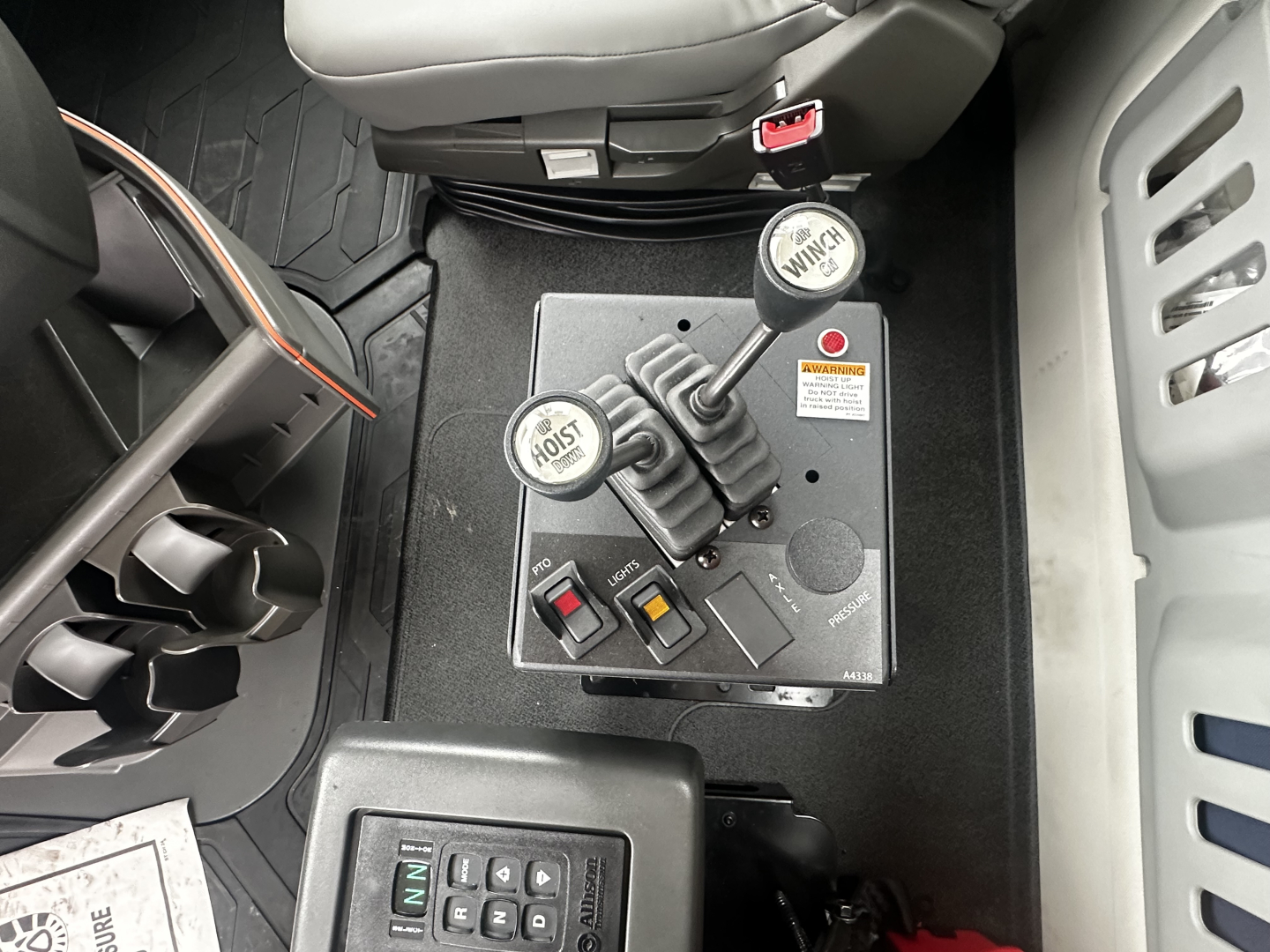 Vehicle interior showing gear selector levers with labeled round knobs and two switches on a control panel in a Volvo VHD truck cabin.