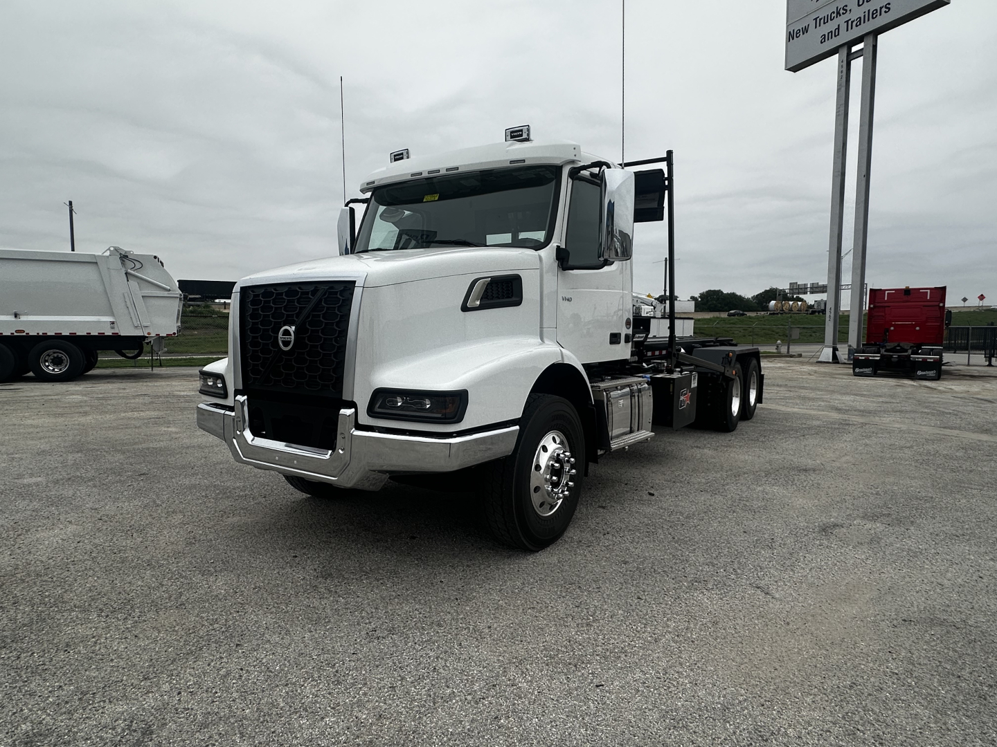 Volvo VHD64B300 truck in white, front-left view showing grille, headlights, and cab; chassis extends to rear with fifth wheel and dual rear axles.