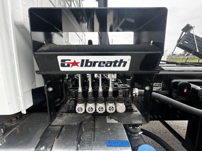 Volvo VHD64B300 roll-off truck showing Cummins/Alternator? No, image shows a Palfinger? Wait. The key visible is a 'Galbreath' hydraulic self-loader? The label reads 'Galbreath' on the machinery near control valves. The image shows the hydr