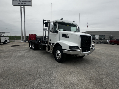 Volvo VHD64B300 rolloff truck in white, front three-quarter view, with chassis extending for container, dealership lot in background.