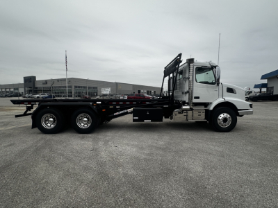 Volvo VHD64B300 rolloff truck side view showing long flatbed with hydraulic arms and cab, VIN 4V5KC9DHXTN710406.