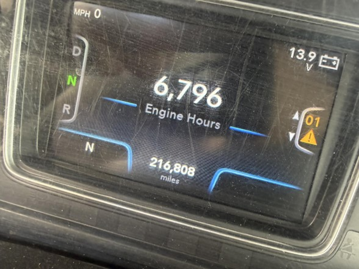 Instrument cluster showing 6,796 engine hours and 216,808 miles in a 2019 International LT625 truck cab; transmission indicator with N and R visible; battery voltage 13.9V.