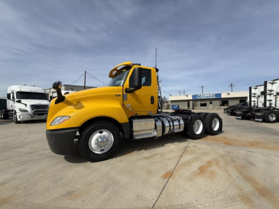 Front-left side of a yellow 2019 International LT625 daycab tractor with chrome fuel tanks and black bumper; dealership lot in background.