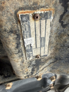 Label plate on engine/transmission area with serials and specs, shows Eaton Transmission, rear axle info, and other stamped identifiers.